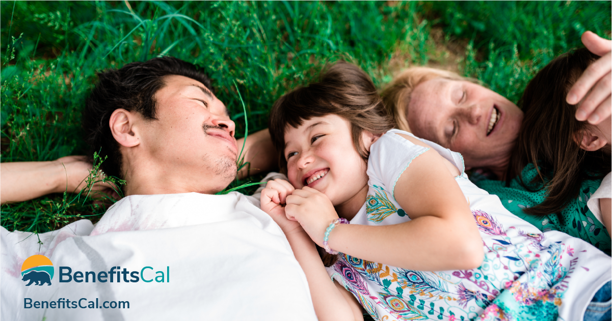 A family laying in the grass with the BenefitsCal.com logo in the bottom left